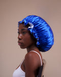 Woman wearing a blue satin hair bonnet against a beige background